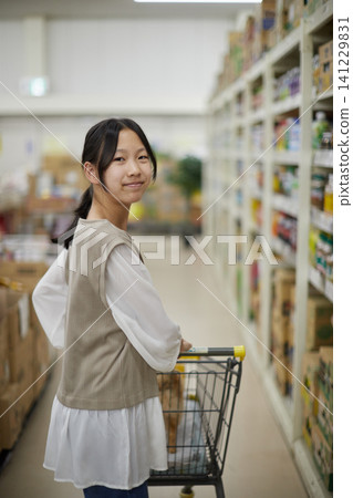 一隻可愛的博美幼犬和一個十幾歲的女孩坐在家居建材商店的購物車上。 一隻可愛的博美幼犬和一個十幾歲的女孩坐在家居建材商店的購物車上。 141229831