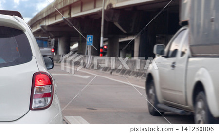 Rear view of white vehicle stationary on a road next to an elevated concrete highway structure. Traffic is visible in the lane during a bright sunny daytime environment. Fast speed of pickup car. Rear view of white vehicle stationary on a road next to an elevated concrete highway structure. Traffic is visible in the lane during a bright sunny daytime environment. Fast speed of pickup car. 141230006