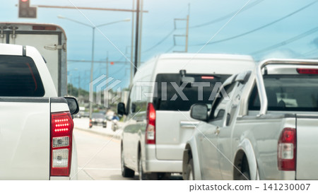 Rear angle shot of various vehicles including a white pickup truck and a van waiting in a line of traffic. Scene captures a typical busy urban commute on a bright day. Rear angle shot of various vehicles including a white pickup truck and a van waiting in a line of traffic. Scene captures a typical busy urban commute on a bright day. 141230007