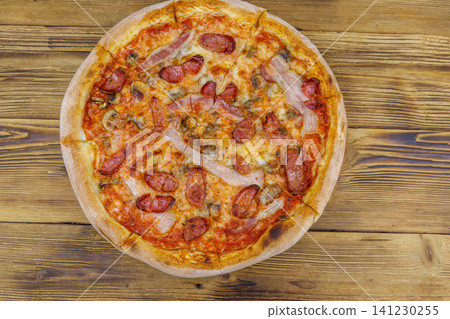 Delicious fresh pizza with sausage, mushrooms and cheese on a wooden table. Top view Delicious fresh pizza with sausage, mushrooms and cheese on a wooden table. Top view 141230255