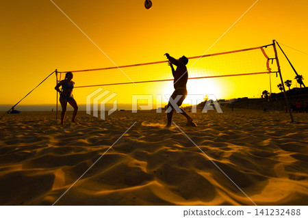 People playing beach volleyball at golden sunset People playing beach volleyball at golden sunset 141232488