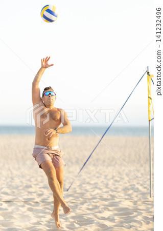 Male athlete playing beach volleyball jumping spiking ball Male athlete playing beach volleyball jumping spiking ball 141232496
