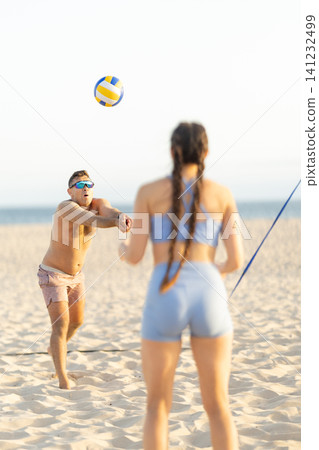 Man and woman playing beach volleyball on a sunny day Man and woman playing beach volleyball on a sunny day 141232499