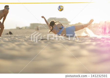 Female athlete diving for ball during beach volleyball Female athlete diving for ball during beach volleyball 141232501