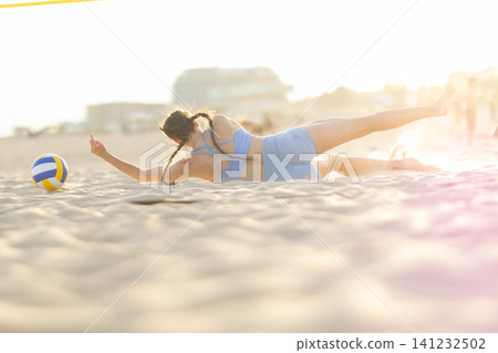 Female beach volleyball player diving for ball on sand Female beach volleyball player diving for ball on sand 141232502