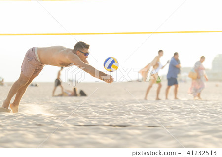 Athlete diving for a beach volleyball serve Athlete diving for a beach volleyball serve 141232513