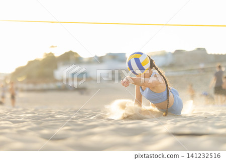 Woman diving for volleyball on sandy beach Woman diving for volleyball on sandy beach 141232516