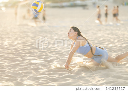 Woman diving for volleyball on sandy beach Woman diving for volleyball on sandy beach 141232517