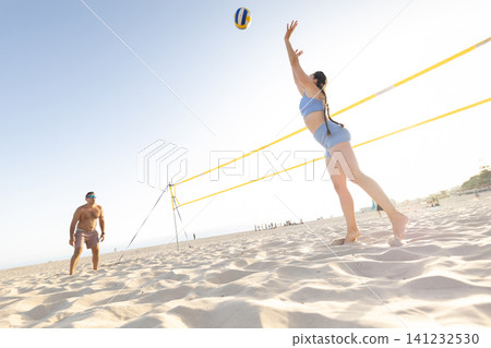 People playing beach volleyball on sand court during summer People playing beach volleyball on sand court during summer 141232530