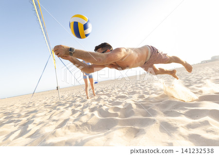 Male beach volleyball player diving for ball Male beach volleyball player diving for ball 141232538