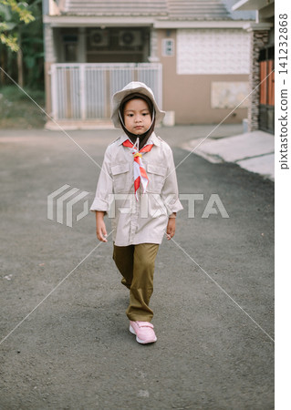Serious young girl in scout uniform walking on residential street Serious young girl in scout uniform walking on residential street 141232868
