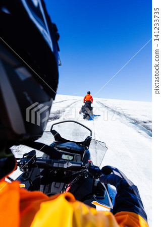 First-person view of a snowmobile tour across a vast Icelandic glacier. Adventure travel through pristine snowfields beneath a dramatic blue sky with wispy clouds in Iceland. First-person view of a snowmobile tour across a vast Icelandic glacier. Adventure travel through pristine snowfields beneath a dramatic blue sky with wispy clouds in Iceland. 141233735