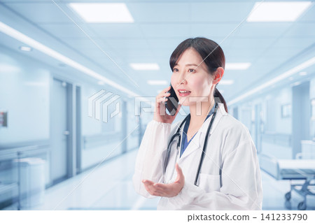 一位女醫生正在使用醫院電話打電話。 一位女醫生正在使用醫院電話打電話。 141233790
