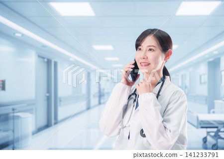 一位女醫生正在使用醫院電話打電話。 一位女醫生正在使用醫院電話打電話。 141233791