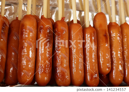A close-up photo of a Frankfurt sausage. Sausage on a stick, festival. A close-up photo of a Frankfurt sausage. Sausage on a stick, festival. 141234557