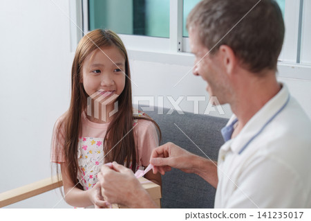 Loving father giving birthday gift to happy daughter at home Loving father giving birthday gift to happy daughter at home 141235017