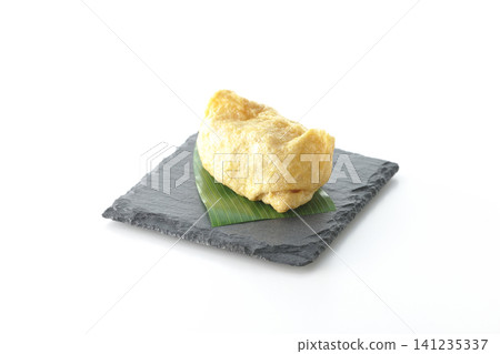 Inari sushi on a slate plate photographed against a white background. 141235337