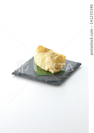 Inari sushi on a slate plate photographed against a white background. 141235340
