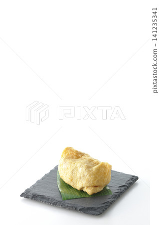 Inari sushi on a slate plate photographed against a white background. 141235341