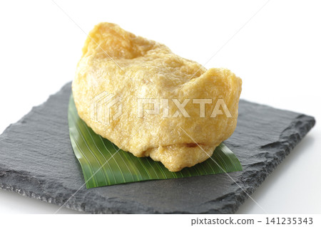 Inari sushi on a slate plate photographed against a white background. 141235343