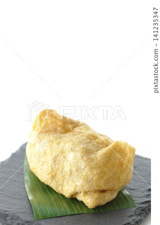 Inari sushi on a slate plate photographed against a white background. 141235347