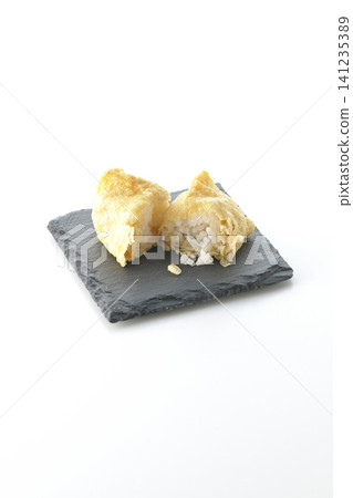 Inari sushi on a slate plate photographed against a white background. 141235389
