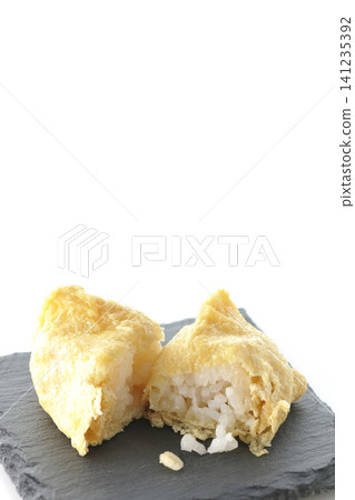 Inari sushi on a slate plate photographed against a white background. 141235392