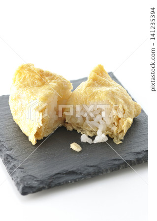 Inari sushi on a slate plate photographed against a white background. 141235394
