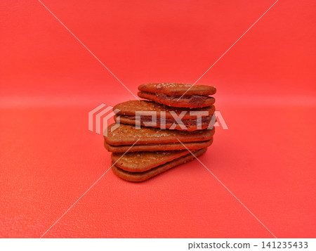 Stack of Heart Shaped Chocolate Sandwich Cookies with Red Filling on Red Background Stack of Heart Shaped Chocolate Sandwich Cookies with Red Filling on Red Background 141235433