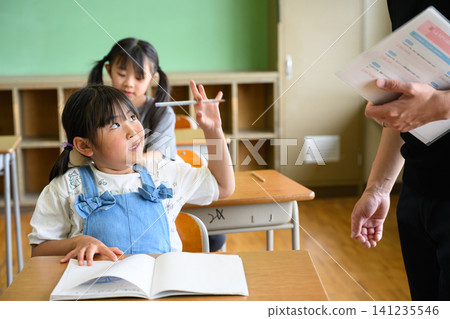 一位男老師正在教室裡看著一位女小學生學習。 一位男老師正在教室裡看著一位女小學生學習。 141235546