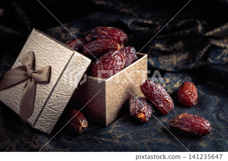 Dates in a gift box on black fabric with gold ornamentation. Dates in a gift box on black fabric with gold ornamentation. 141235647