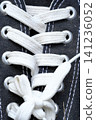 A close-up shot of white shoelaces on a black shoe. 141236052