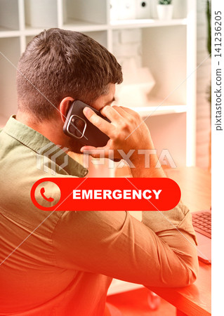 Man calls emergency services while seated at a desk in an office space during daytime 141236205