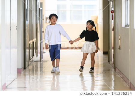 A boy and a girl, both elementary school students, walking down the school corridor hand in hand. A boy and a girl, both elementary school students, walking down the school corridor hand in hand. 141236234