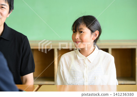 一位女教師、一位父親和一位小學生在教室裡進行了一場友好而愉快的三方會面(職業指導/輔導)。 一位女教師、一位父親和一位小學生在教室裡進行了一場友好而愉快的三方會面(職業指導/輔導)。 141236380