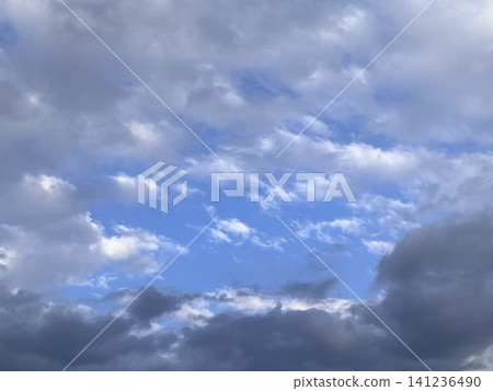 湛藍的天空透過厚厚的雲層縫隙顯露出來。光影交錯，構成了一幅引人入勝的背景。 141236490