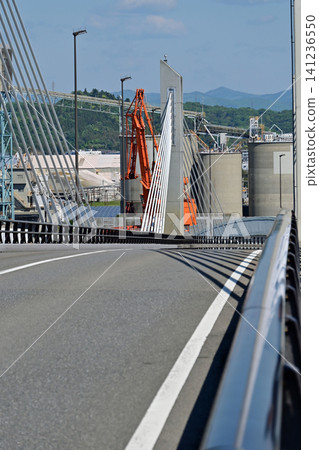 A clear, sunny day at the Onahama Marine Bridge, which is open to the public. A vertical composition of the roadway and the coastal industrial area/factories viewed from the top. 141236550