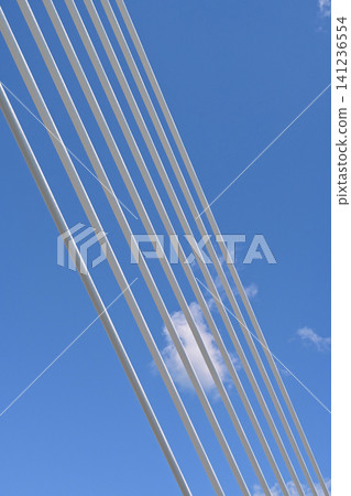 A vertical composition image of white cable-stayed cables lined up against a clear blue sky, taken during the public opening of the Onahama Marine Bridge on a sunny day. A vertical composition image of white cable-stayed cables lined up against a clear blue sky, taken during the public opening of the Onahama Marine Bridge on a sunny day. 141236554