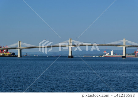 A beautiful, clear day with a horizontal horizon, a distant view of Onahama Port and Onahama Marine Bridge, and a landscape featuring large ships. 141236588