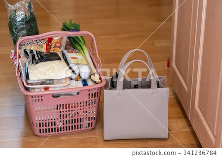 A scene after returning home, where groceries are placed in a shopping basket and left by the front door. 141236784