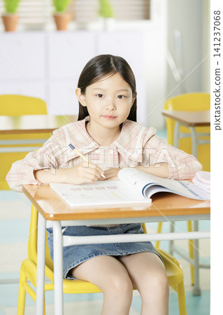 Smiling elementary student studying at a classroom desk Smiling elementary student studying at a classroom desk 141237068