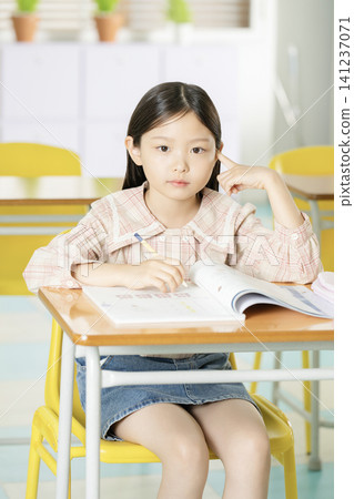 Smiling elementary student studying at a classroom desk Smiling elementary student studying at a classroom desk 141237071