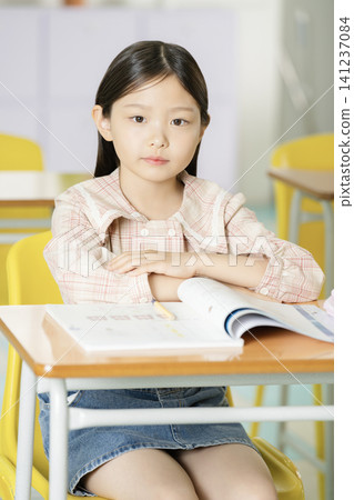 Young schoolgirl concentrating on lessons in a cheerful classroom Young schoolgirl concentrating on lessons in a cheerful classroom 141237084