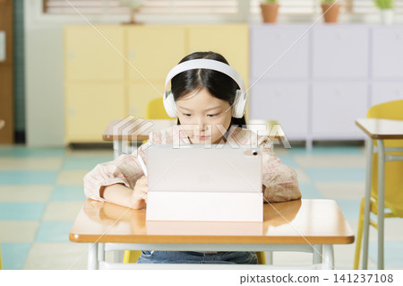 Young student learning online with a laptop in class Young student learning online with a laptop in class 141237108