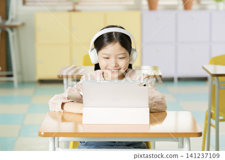 Elementary schoolgirl using a laptop at a classroom desk Elementary schoolgirl using a laptop at a classroom desk 141237109