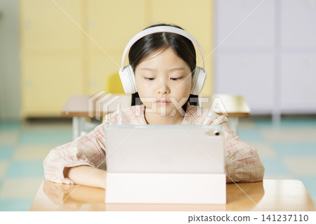 Asian schoolgirl studying on a laptop in a bright classroom Asian schoolgirl studying on a laptop in a bright classroom 141237110
