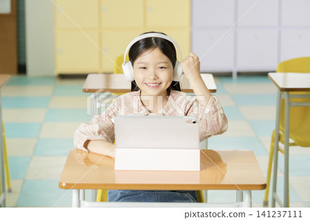 Asian schoolgirl studying on a laptop in a bright classroom Asian schoolgirl studying on a laptop in a bright classroom 141237111