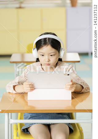 Elementary schoolgirl using a laptop at a classroom desk 141237112