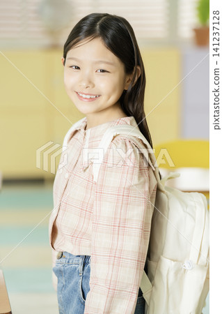 Schoolgirl wearing a backpack in an elementary school classroom Schoolgirl wearing a backpack in an elementary school classroom 141237128