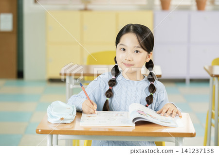 Young schoolgirl raising her hand while studying in class Young schoolgirl raising her hand while studying in class 141237138